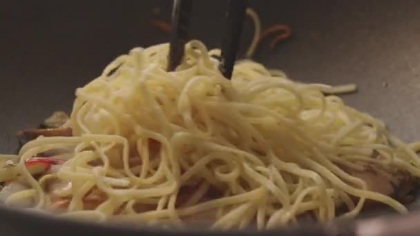 Kuchař připraví nudle se zeleninovou směsí špaget podávaných v černé železné pánvi — Stock video