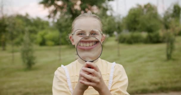 Loupe divertimento bambini sorriso con una lente d'ingrandimento godere di lui fa grandi denti — Video Stock