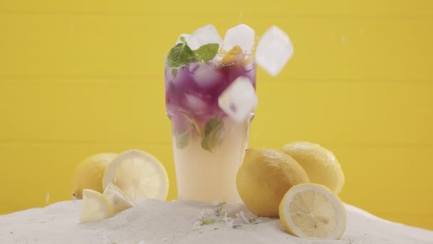 Cóctel de limonada de verano con menta helada y cítricos en rodajas sobre fondo amarillo — Vídeo de stock