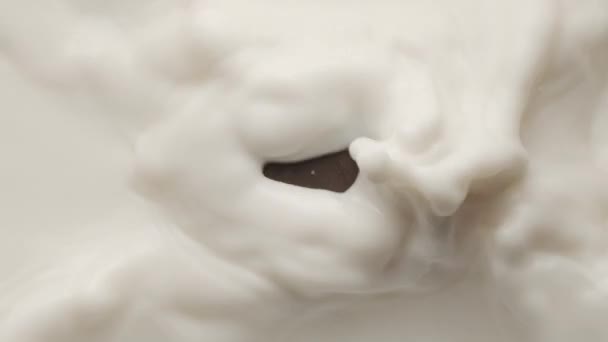 Cioccolato quadrato che cade in una ciotola di latte e rendendo corona e increspature circolari — Video Stock