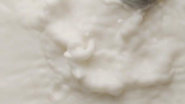 Круглый шоколад падает в молочную миску и делает корону и круглые струйки — стоковое видео