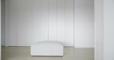 Koridorda küçük bir kanepesi olan beyaz dolapları olan modern beyaz bir daire.