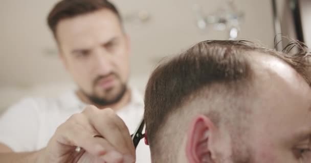Il parrucchiere taglia i capelli all'uomo in barbiere, ottenendo un taglio di capelli moderno — Video Stock