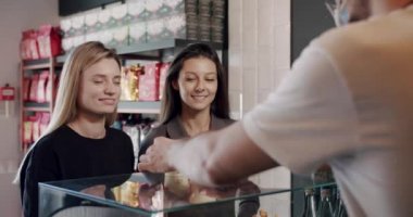 İki güzel kız kahve bekliyor. Kahveci kahve servisi yapıyor.