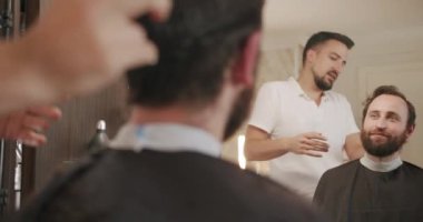 Berber dükkanında oturan şık adam kuaför, tarak düzenleme.