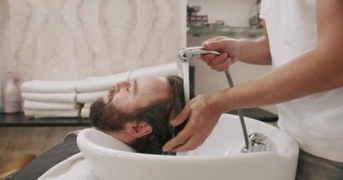 Profesyonel bir güzellik salonu çalışanı müşteri saçını suyla ve masajla yıkıyor.