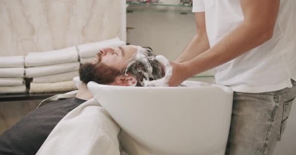 男性在美发师按摩、洗发水洗头时谈话和放松 — 图库视频影像