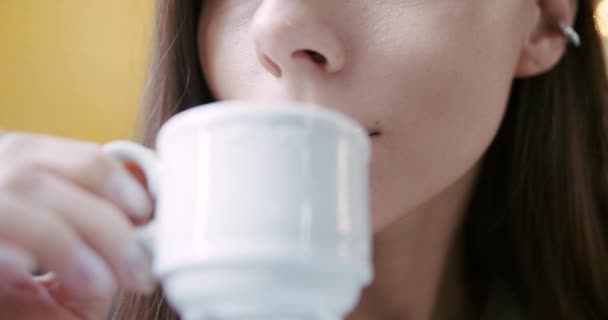 Κοντινό πρόσωπο μιας γυναίκας που πίνει καφέ. Χαμογελάει και το απολαμβάνει με ένα φλιτζάνι τσάι. — Αρχείο Βίντεο