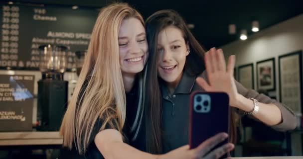 Atrakcyjne młode kobiety wykonujące rozmowy wideo przez telefon komórkowy zrobić w kawiarni, czat — Wideo stockowe
