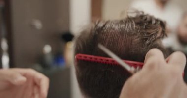 Berber dükkanında oturan şık adam kuaför, tarak düzenleme.