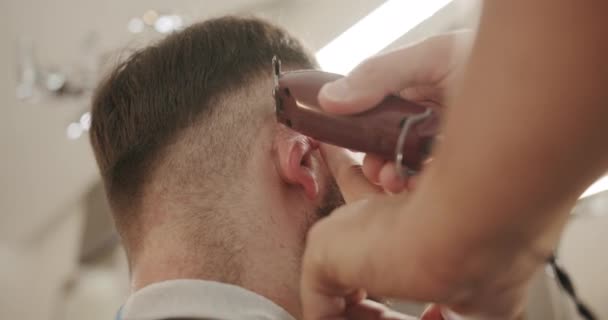 Frisören ger bleknad frisyr till en manlig klient. skott av kort klippare frisyr — Stockvideo