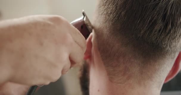 Fryzjer daje blakniętą fryzurę męskiemu klientowi. ujęcie krótkiej fryzury clipper — Wideo stockowe