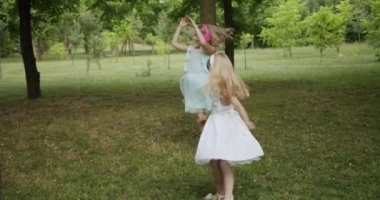 Mutlu çocuklar dans eder ve parkta müzik dinler. Kız kardeşler gündüz döner.