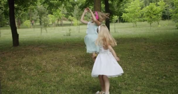 Fröhliche Kinder tanzen und hören Musik im Park, die Schwestern drehen den Tagesmodus — Stockvideo