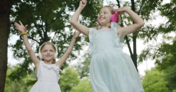 Beste Schwestern tanzen und hören Musik im Park, fröhliche Kinder tanzen — Stockvideo