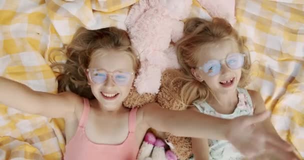 Неожиданный сюрприз, маленькие девочки улыбаясь в очках смотрит в камеру, праздники — стоковое видео