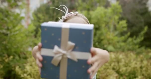 Gadis kecil yang cantik, dia memberikan kotak hadiah, membuat hadiah kecil dalam kotak pada hari ulang tahun — Stok Video