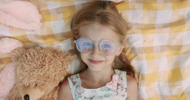 Niña sonriendo con gafas sin un diente y mira a la cámara de video llamada — Vídeos de Stock