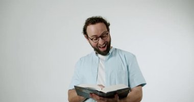 Gözlüklü ve sakallı neşeli bir adam kitap okumaktan hoşlanır. Hikayeye hayran kalmış, sayfaları çevirirken gülümsüyor ve gülüyor. İçeriği eğlenceli ve çekici buluyor..