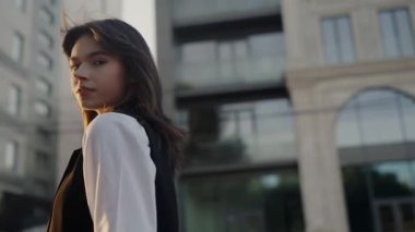 Kendine güvenen, gündelik kıyafetli genç bir kadın şehirde duruyor, profesyonellik ve modernlik yayıyor. Kentsel Ayarlarda Günlük İş Giyimi İçinde Genç Kadın