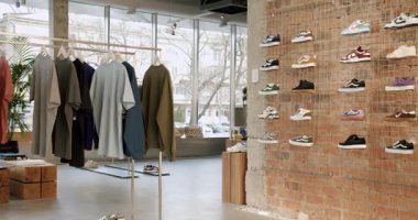 Kıyafetleri ve ayakkabıları olan modaya uygun bir giyim mağazası. Modern mağazanın içinde tuğla duvar ve metal raflar var. Moda ayakkabılı şehir moda butiği. Chisinau, Moldova - 18 Ocak 2025