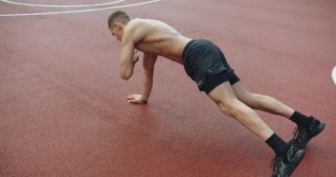 Atletik adam dışarıda yoğun antrenman yapıyor ve çapraz antrenman yapıyor. Atletik adamın dışarıda yoğun bir antrenmanı var. Genç kaslı erkek spor sahasında çapraz antrenman yapıyor ve egzersiz yapıyor..