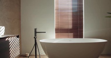 Beyaz, serbest bir küvet, çağdaş bir kibir ve ahşap panjurların arasından süzülen güneş ışığının bulunduğu modern banyo rahatlatıcı, sakin bir atmosferi arttırıyor. Zarif Modern Tuvalet