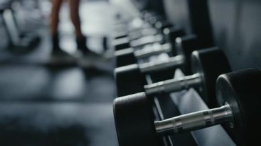 Modern bir spor salonunda ağırlık kaldırma ve ağırlık kaldırma antrenmanına odaklanmış halterdeki ağır bir dambıl için uzanan bir elin yakın çekimi. Modern Spor Salonundaki Salağın Eline Yakından Yaklaş