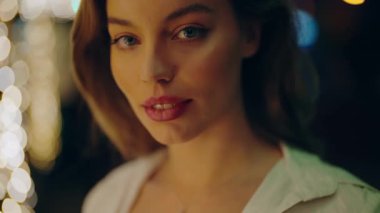 Güzel bir kadının yakın plan çekimleri, narin bir gülümseme ve arka planda yumuşak ışıklar, sıcak ve büyülü bir atmosfer yaratıyor. Geceleri arka planda yumuşak ışıklarla gülümseyen güzel bir kadın.