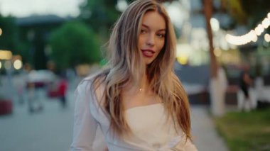 Neşeli bir yüzü olan kaygısız bir kadın şehir parkında eğleniyor. Saçları rüzgârla savruluyor, mutluluğu ve özgürlüğü yansıtıyor. Genç ve güzel bir kadın Açık havada eğleniyor.