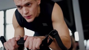 Kararlı bir genç, spor salonunda spor yapıyor, spor salonunda spor yapıyor ve kendini adamış. Odaklanmış Erkek Sporcu Spor Salonunda Yoğun Egzersiz Bisikleti Eğitimi