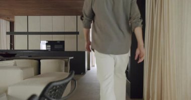 Şık bir adam lüks ve konforun altını çizerek zarif, minimalist bir dekorla modern, iyi döşenmiş bir evde yürüyor. Modern Tarzda Yürüyen Ev İçi, Zarif Tasarım