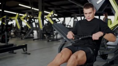 Modern bir spor salonunda spor yapan atletik bir adamın görüntüsü bulanık. Odaklanmış yaklaşımını ve spor aletlerini vurguluyor. Modern Spor Salonu 'nda Egzersiz Yapan Genç Adam Yoğun Odaklanma