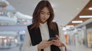 Modern bir alışveriş merkezinde telefonuyla konuşan genç bir iş kadını. Alışveriş merkezinde Smartphone 'da Profesyonel Kadın Mesajlaşması