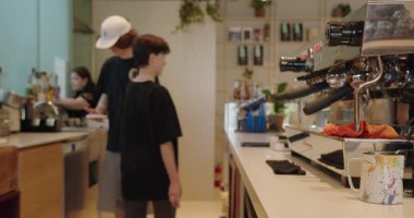 Modern bir kahve dükkanında, erkek ve kadın baristaların siparişleri hazırladığı aktif bir sahne. Bulanık hareket dinamik bir his katıyor, Chisinau - Moldova. 27 Temmuz 2023