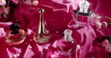 Çiçekler ve incilerle süslenmiş pembe saten kumaş üzerinde sergilenen çeşitli zarif parfüm şişelerinden oluşan güzel bir düzenleme. Lüks, kadınlık ve entelektüellik yayar. Zarif parfüm şişeleri