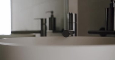 Modern minimalist bir banyo lavabosunun modern ortamında şık bir musluğu olan yakın plan. Temiz, gösterişli tasarım ve nötr tonlar zarif ve sakin bir atmosfer yaratır..