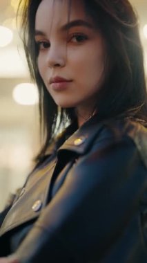 Deri ceketli şık bir kadın. Geceleri kendine güvenen bir ifadeyle. Deri ceketli, kendine güveni ve tavırları olan şık bir genç kadının portresi. Gece ayarı biraz gizem katıyor..