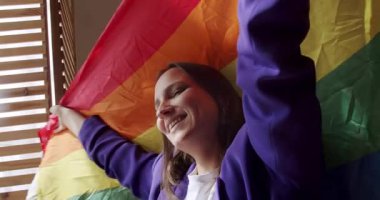 Lgbt kadınları evde gökkuşağı bayrağıyla dans ediyorlar. Sarıl ve tut. LGBT Gurur Ayı, mutlu lezbiyen bayan portresi. LGBT hakları, lezbiyen ailesi. Yaşam tarzı ve ilişkiler. LGBT kavramı