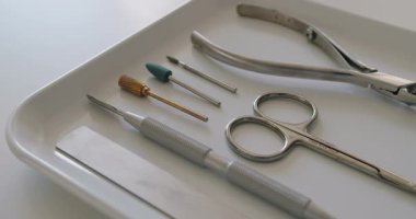 Tırnak eti, paslanmaz çelik satıcı, meme uçları, makas ve hortumlar. Tırnak tedavisi için profesyonel aletler. Güzellik salonundaki beyaz masada kullanıma hazır profesyonel manikür aletleri..