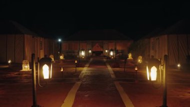 Geceleri Sahra Çölü 'nde Glamping, Fas' ta. Fenerler Bedevi çadırlarına giden yolu aydınlatır. Romantik kaçamak, macera seyahati ya da doğada barışçıl bir dinlenme. Ilık parıltı büyülü bir ortam yaratır..