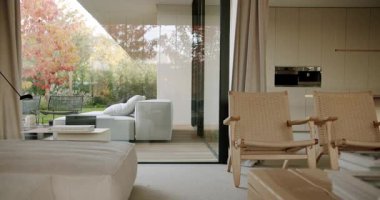 Rahat mobilyaları ve güzel bir bahçeye bakan geniş pencereleri olan modern oturma odası. Doğal ışık odayı doldurur. Rahat ve rahatlatıcı bir atmosfer yaratır..