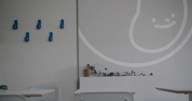 Modern ofis alanı beyaz bluzlu bir kadın kısmen görünür, şık iç tasarım minimalist dekor ile ve duvarda dostça bir çalışma atmosferini destekleyen büyük bir gülümseme ikonu.