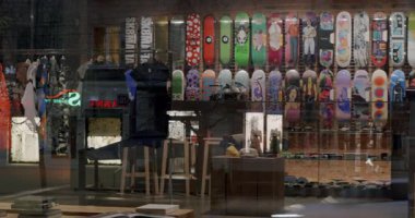 Geceleri şehir modası ve kaykay dükkanı vitrinleri. Renkli kaykaylar, moda giysiler ve aksesuarlar modern sokak giyimi kültürünü yansıtıyor.