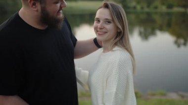 Sevecen bir çift, huzurlu bir gölün yanında, huzurlu bir ortamda neşe ve aşkı yansıtan hassas bir anı paylaşır. Gölün kenarında dingin bir anın tadını çıkaran romantik çift.