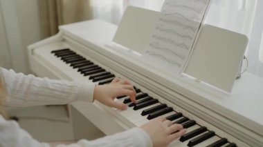 Genç kız evde piyano çalışıyor. Eğitim ve öğrenim geliştirme konsepti. Ev müziği stüdyosu kadını. Müzik eğitimi. Eller piyano tuşlarına basıyor. Nota okuyorum. Piyano öğrenme dersleri