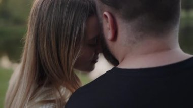 Bir çiftin açık havada sevgi dolu bir bakışını paylaştığı samimi bir an, sıcaklığı ve sevgiyi dingin bir arkaplan ile anımsatıyor. Alacakaranlık, Şefkatli Bakış 'ta Sevgili Çift Arasında Romantik Bir An