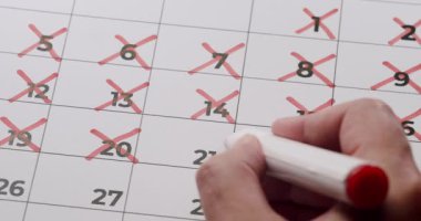 Takvim tarihlerini kırmızı kalemle silmek geri sayımı ya da takibi işaret ediyor. Zaman yönetimi kavramı, teslim tarihleri ve planlama olayları.