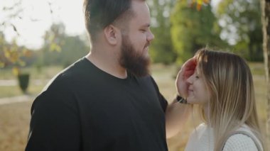 Genç bir çift, bir sonbahar parkında sevgi dolu bakışlarını paylaşıyor, sakin bir açık hava ortamında yakınlık ve yakınlık anlarını yakalıyorlar. Romantik Çift Sonbahar Parkı 'nda İhale Anlarının tadını Çıkartıyor