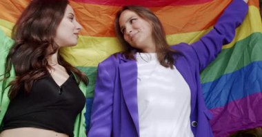 Bir çift, Igbt ve lezbiyen kadınlar gururlu gökkuşağı bayrağıyla evlerinde. Sarılın ve birbirinize sarılın. Sevgi. LGBTQI, Onur Etkinliği, LGBT hakları, lezbiyen ailesi. Yaşam tarzı ve ilişkiler. LGBT kavramı